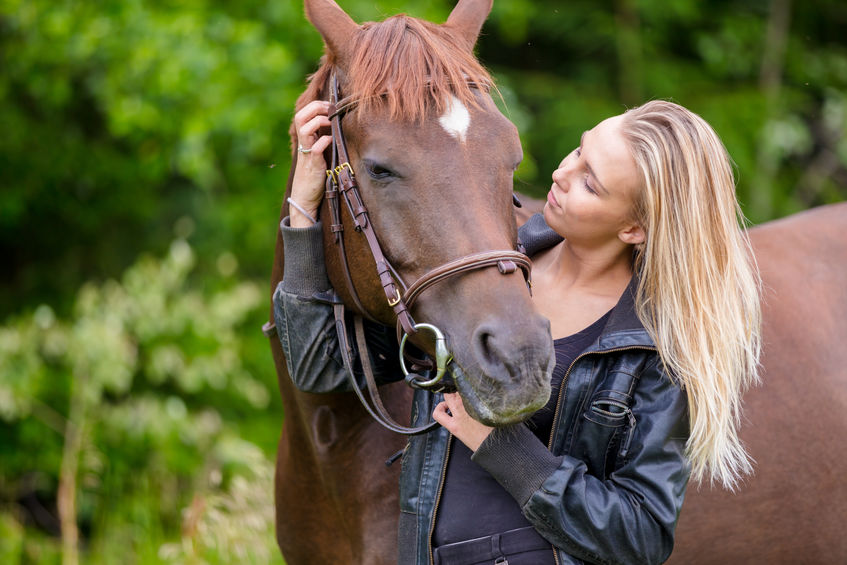 Young woman with her arabian horse standing in the field